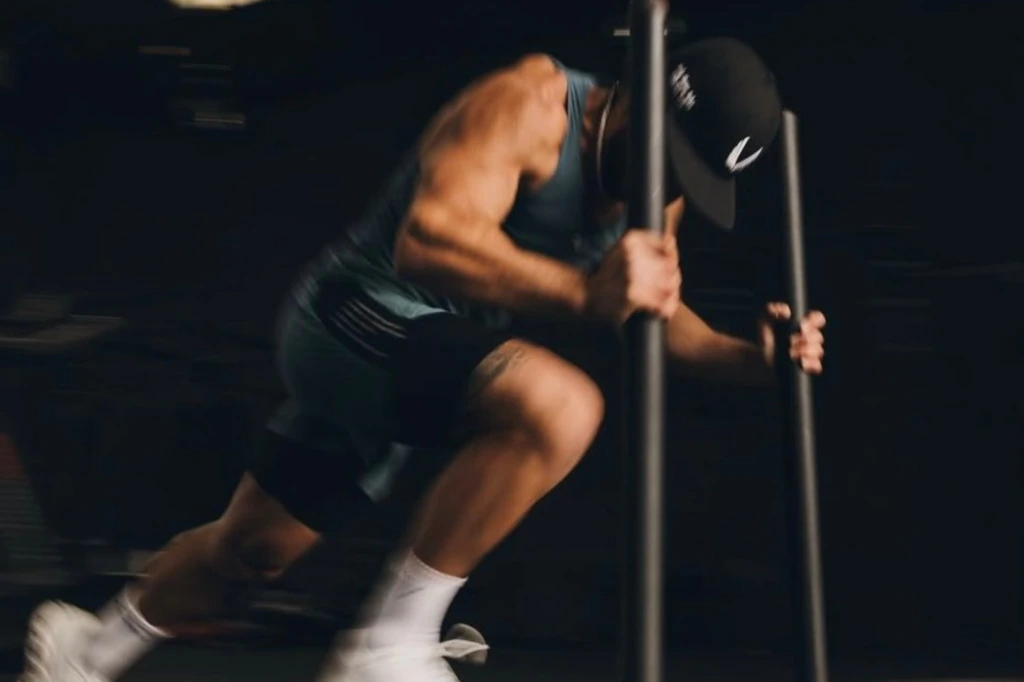 Atleta in box ibrido spinge lo sled durante una simulazione HYROX