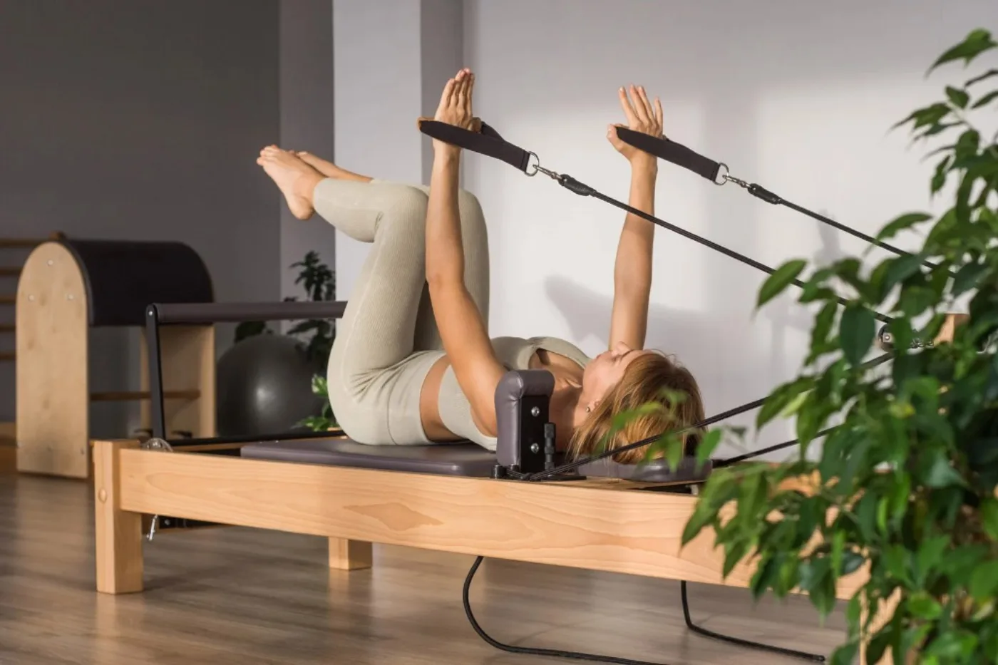 Istruttrice sul reformer in studio luminoso durante un esercizio di pilates.